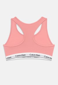 Różowy sportowy stanik z plecami w kształcie wyścigowym z białą elastyczną taśmą, na której powtarza się czarny napis Calvin Klein.