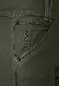 Zelené látkové kalhoty s hladkým povrchem, obsahující přední kapsu s černým knoflíkovým kováním a kontrastním prošíváním.