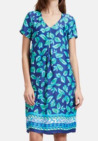 Vestido de manga corta en tela azul con patrones de hojas verdes, escote en V y una banda decorativa cerca del dobladillo en blanco y azul.