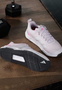 Hellrosa Sportschuhe mit strukturierter Mesh-Oberseite, weißen Akzenten und einer schwarzen Gummisohle mit geometrischem Profil.