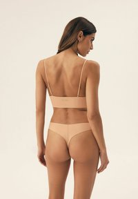 Nude komplet bielizny składający się z formowanej biustonosza na cienkich ramiączkach oraz pasujących bikini. Gładka struktura, bezszwowy design, minimalna widoczność logo.