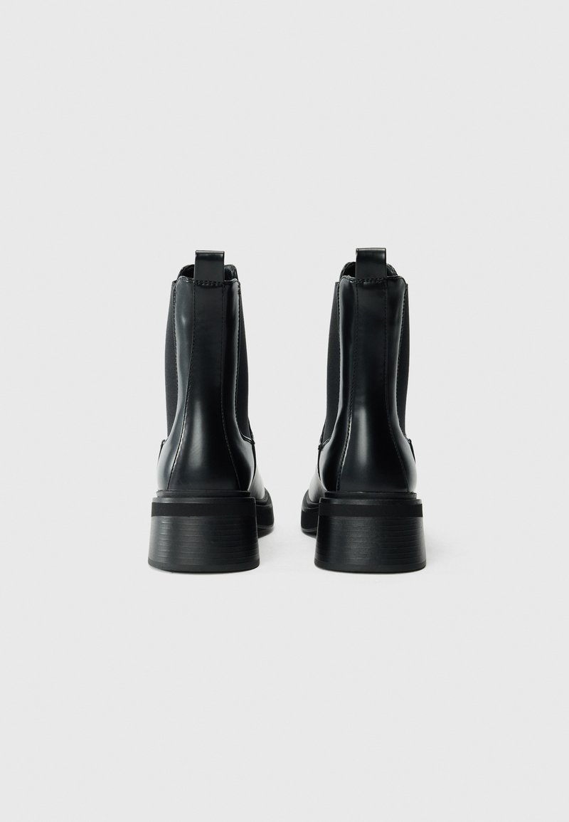 Bottines en cuir noir avec des panneaux latéraux élastiques et des languettes. Semelles en caoutchouc épaisses et texturées offrant adhérence et stabilité.