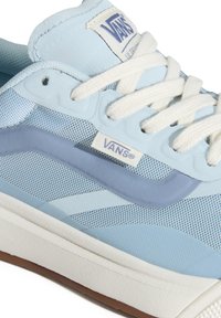 Baskets Vans bleu clair avec lacets blancs, dessus en mesh et suède, bande latérale bleu plus foncé, et semelle blanche avec rainures marron.