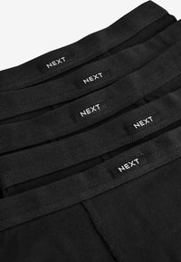 Musta aluspesu elastse vöökohtaga, millel on "NEXT" logo. Sile kangas ja lihtne disain, virnastatud ritta.