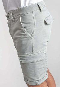 Lichtgrijze cargoshorts van een zachte, gestructureerde stof. Voorzien van zijzakken en opgerolde zomen, met opvallende stikselaccenten.