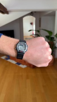 Digitalna ura Casio s črnim silikonskim paščkom, srebrnim robom in večfunkcijskim zaslonom, ki prikazuje čas, datum in nastavitve alarma.