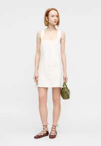 Λευκό λινό φόρεμα με τετράγωνο ντεκολτέ και κουμπιά μπροστά, συνδυασμένο με τσάντα χακί ελιάς και μπορντό παπούτσια με κορδόνια. Λεία υφή.