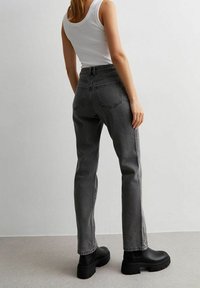 Šedé džínové kalhoty s vysokým pasem, rovný střih nohavic a zadními kapsami. Vypadají skvěle s černými platformovými kotníkovými botami a bílým tílkem.