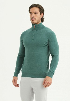 Veste zippée verte en tissu tricot léger, avec un col haut, des poignets côtelés et un ourlet, dotée d'une texture subtile sur l'ensemble.