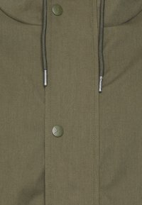 Veste vert olive vue de face avec deux boutons ronds mats et cordons noirs terminés par des embouts en métal argenté.