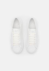 Witte leren sneakers met een gladde afwerking, ronde neus en platte witte veters. Minimalistische merkvermelding op de tong en zijkant.