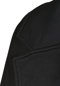 Tessuto di felpa nera con una texture liscia e dettagli a coste sulle spalle. Presenta uncollo piatto e dettagli cuciti.