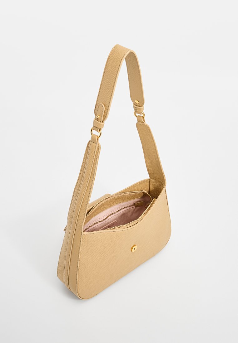 Beige handtasche aus leder mit strukturierter oberfläche, goldfarbene hardware-akzente und einem mit pinkem futter versehenen reißverschlussfach.