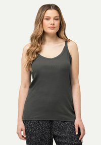 Top senza maniche di un verde scuro con scollatura a V, realizzato in tessuto liscio. Abbinato a pantaloni scuri a fantasia con piccoli disegni floreali.