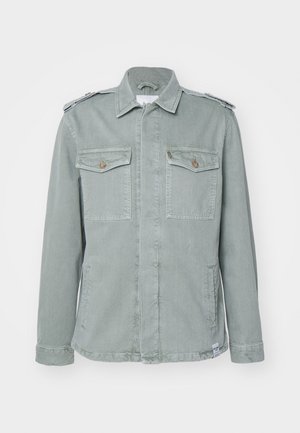 Vihreä denim-takki, jossa on sotilasmallinen muotoilu. Takissa on kaksi rintataskua, hartiapelejä ja suora leikkaus. Pintakuvio on sileä.