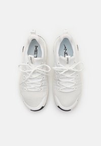 Weiße Sportschuhe mit einem Obermaterial aus Mesh, runder Zehenpartie, flachen Schnürsenkeln und einer gummierten Sohle. Besitzt ein weiches Innenfutter und minimales Branding.