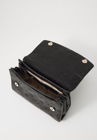 Sort læder håndtaske med præget logo mønster, gyldne hardware-lukninger og en struktureret overflade. Indvendigt har den en lysere foret med rum.