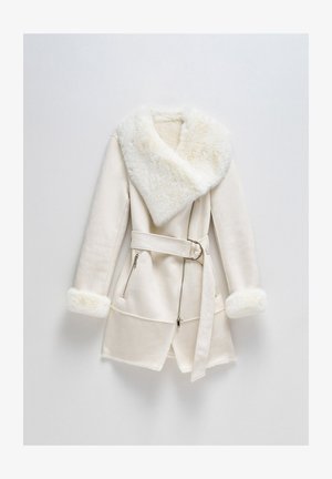 Cappotto bianco lungo con un colletto e polsini in pelliccia sintetica morbida. Presenta una vita con cintura, tasche con zip e un orlo asimmetrico.