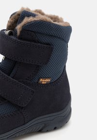 Stivaletti per bambini blu navy con un upper in tessuto testurizzato e scamosciato, cinturini in velcro e una morbida fodera interna beige per il calore.