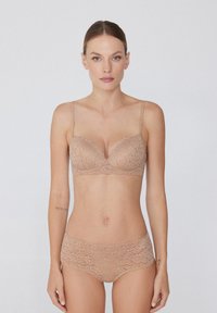 Conjunto de sujetador de encaje y braguita a juego en color nude con patrón floral. Tirantes ajustables y bordes en forma de ondas en el sujetador. Textura suave.