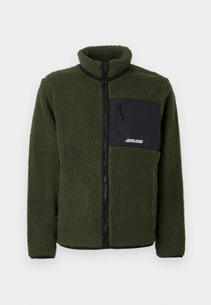 Jachetă din fleece verde cu un buzunar negru cu fermoar, guler înalt și decoruri negre contrastante de-a lungul fermoarului și la manșete. Material texturat.