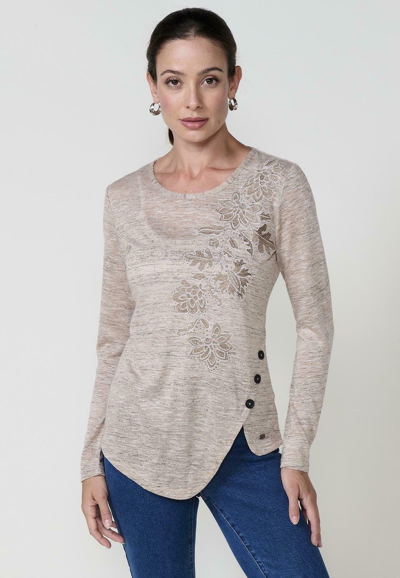 Beige Langarmoberteil mit gemusterter floralem Bordüre auf der linken Seite, schwarzen Knöpfen auf der rechten Seite und einem abgerundeten Saumdesign.