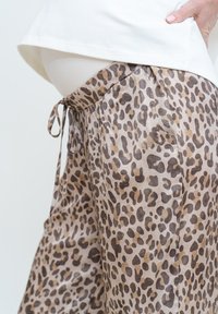 Leopardmönstrade, lätta tygbyxor med elastisk midja och justerbart snöre, i nyanser av beige och brunt.
