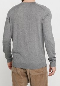 Grå tröja i mjuk stickad tyg, med rund halsringning, långa ärmar och ribbade muddar och nederkant, med en slät textur.