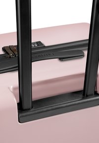 Hartschalenkoffer in Rosa mit schwarzen teleskopischen Griffen, Reißverschluss und Kombination Schloss. Glatte Textur und abgerundete Kanten.