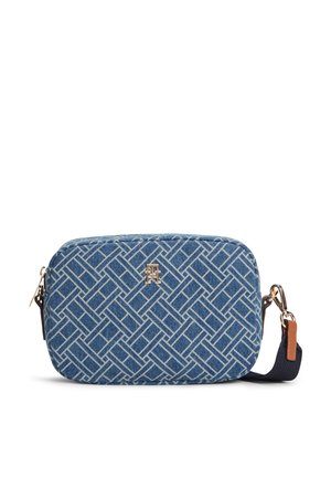 Sac bandoulière rectangulaire bleu avec motif géométrique blanc, emblème logo doré, fermeture éclair, et sangle amovible marine avec accent en cuir marron.