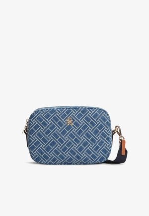 Modrá obdélníková kabelka přes rameno s bílým geometrickým vzorem, zlatým logem, zapínáním na zip a odnímatelným tmavě modrým popruhem s hnědým koženým detailem.