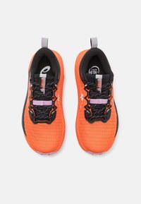 Baskets de sport orange vif avec des accents noirs, dessus en maille texturée, lacets noirs et détails violets sur la languettes du talon et la semelle.