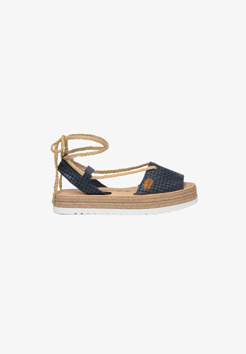Sandalia espadrille con parte superior de nailon tejido en color azul marino, con un lazo de cuerda natural en el tobillo, plantilla de corcho y suela de plataforma envuelta en yute con suela exterior de goma blanca.