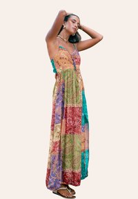 Vestido maxi con un diseño de patchwork en múltiples colores, que presenta patrones de cachemira. Fabricado con una tela liviana, tiene una silueta fluida y tirantes finos.