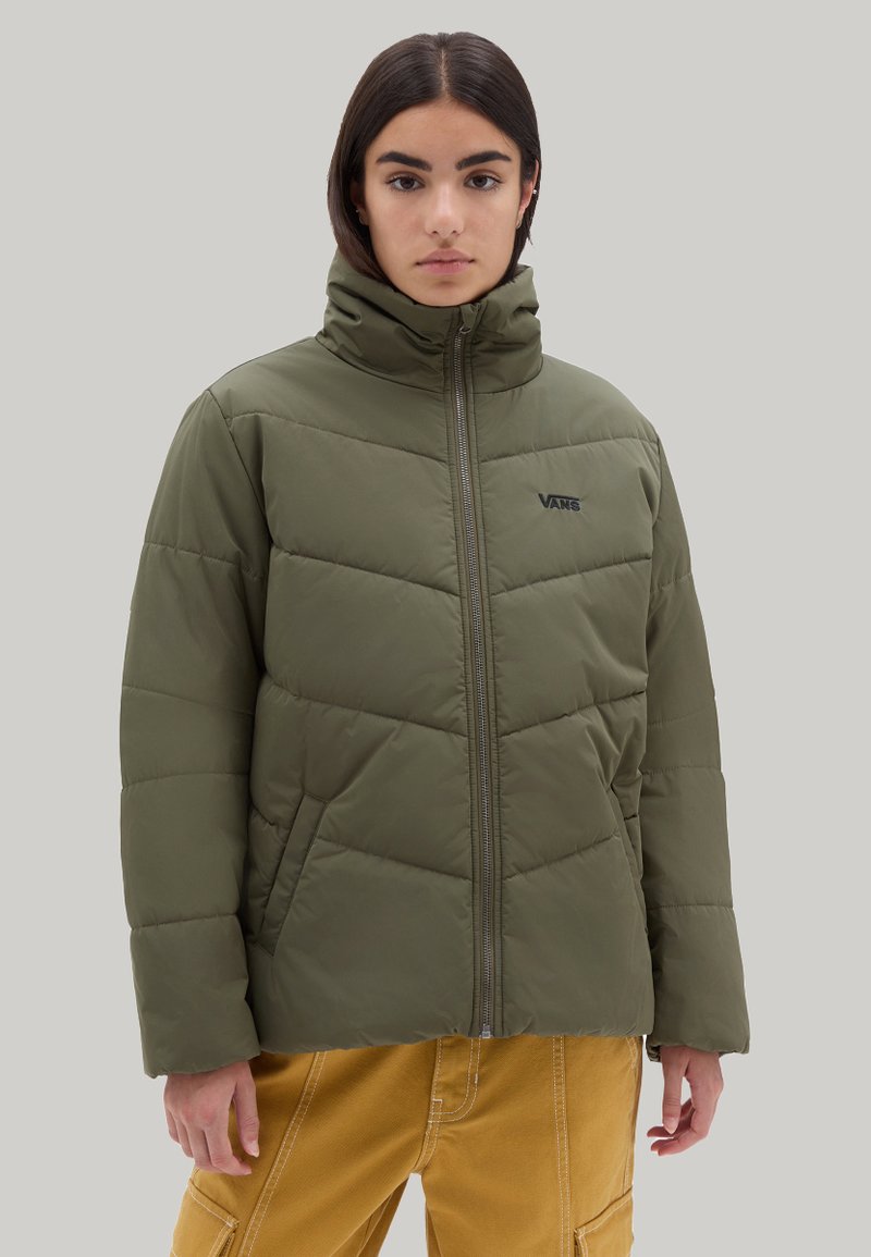 Chaqueta acolchada verde oliva con cuello alto, cierre de cremallera, textura acolchada y logotipo negro en el lado izquierdo del pecho. Indicado para uso en nieve o invierno.