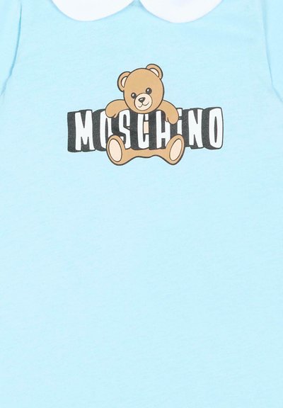 Lyseblåt tøjstykke med hvid rund krave og en bamse, der holder bogstaverne "MOSCHINO" tværs over brystet.