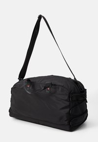 Sac de sport en tissu noir avec une bandoulière ajustable, des poignées supérieures, des détails en rouge et des cordons bungee sur le côté pour un rangement supplémentaire.