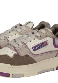 Sneaker bianchi e beige con accenti viola, materiali in suede e pelle, punta rotonda, design con lacci, suola testurizzata con blocchi di colore.