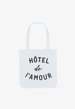 Borsa in cotone bianca con testo nero che recita "HÔTEL de l'amour." Presenta due manici robusti e un design spazioso.