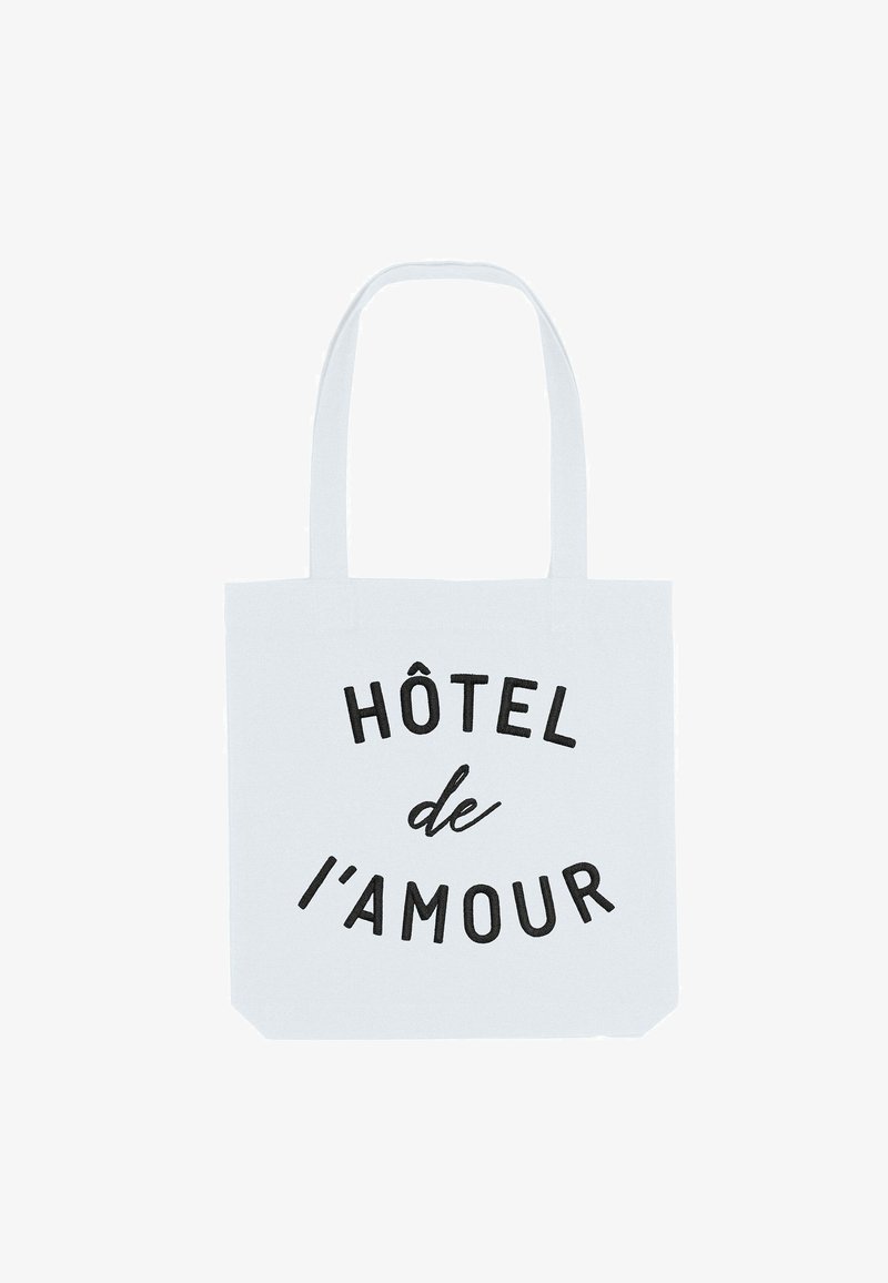 Witte katoenen draagtas met zwarte tekst "HÔTEL de l'amour." Voorzien van twee stevige handvatten en een ruime ontwerp.
