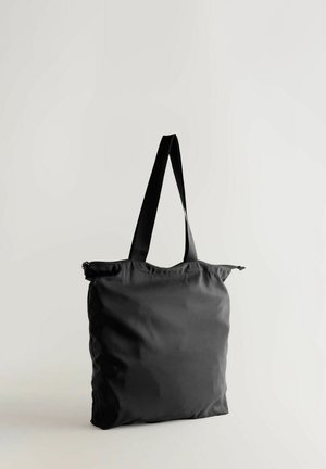 Černá taška typu tote z měkké texturované látky, vybavená dvěma dlouhými, plochými držadly a zipem na vrchu. Jednoduchý, obdélníkový design.