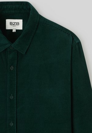 Chemise en velours côtelé vert foncé avec un col pointu, une fermeture à boutons et une texture légèrement côtelée. L'étiquette indique "BZB Comfort", taille L.
