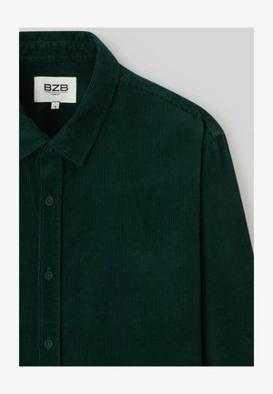 Chemise en velours côtelé vert foncé avec un col pointu, une fermeture à boutons et une texture légèrement côtelée. L'étiquette indique "BZB Comfort", taille L.