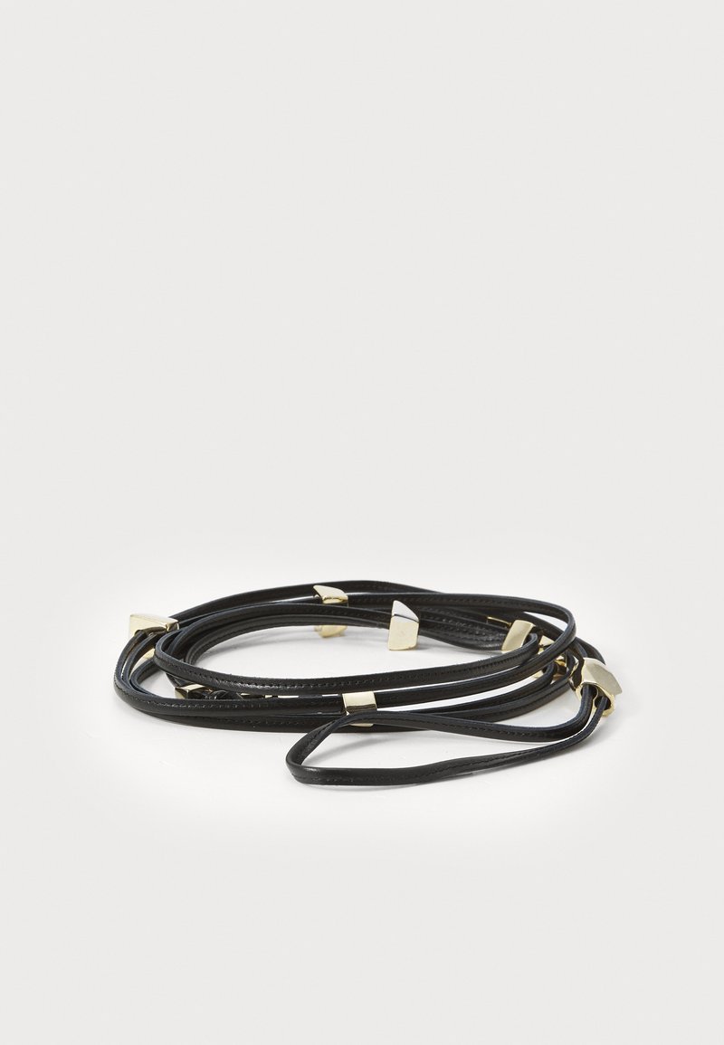 Pulseira de couro preto com acabamentos em metal dourado, apresentando uma textura suave e um design em laço. Inclui detalhes em hardware triangular notáveis.