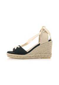 Sandalo con zeppa in suede nero e suola in juta intrecciata beige, design open toe, lacci alla caviglia e accentuazione a tacco testurizzato.