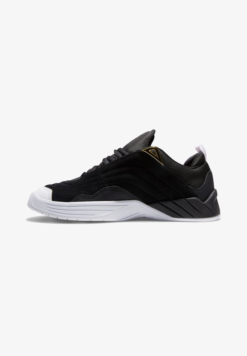 Svart sneaker laget av semsket skinn og syntetiske materialer, med såle i hvitt gummi, teksturerte sider og gull detaljer på hælen.