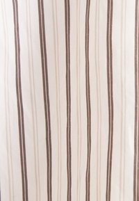 Tissu beige avec des rayures verticales dans différentes nuances de marron et crème, espacées uniformément sur tout le matériau.