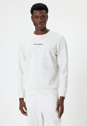 Lys grå sweatshirt med struktureret mønster, rund halsudskæring og grafisk tryk "FIND DIN ADVENTURE" i sort. Ribbet manchetter og kant.
