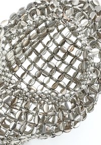 Bracciale in metallo argentato con un design intrecciato, caratterizzato da perle ovali e rotonde. Superficie liscia con finitura lucida e struttura leggera.