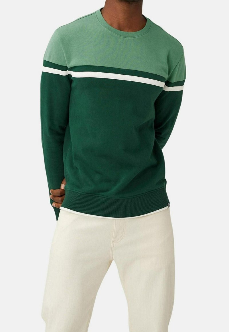 Sudadera de mezcla de verde y verde claro con cuello redondo, presenta rayas blancas horizontales a lo largo del pecho y puños acanalados.